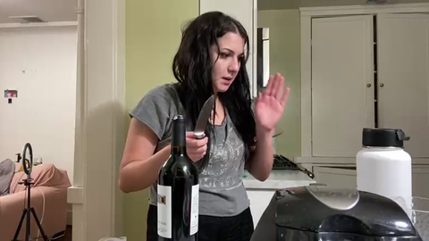 Girl clearly on something, opens wine bottle with scissors