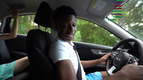 Rakai looking at camera and phone while driving