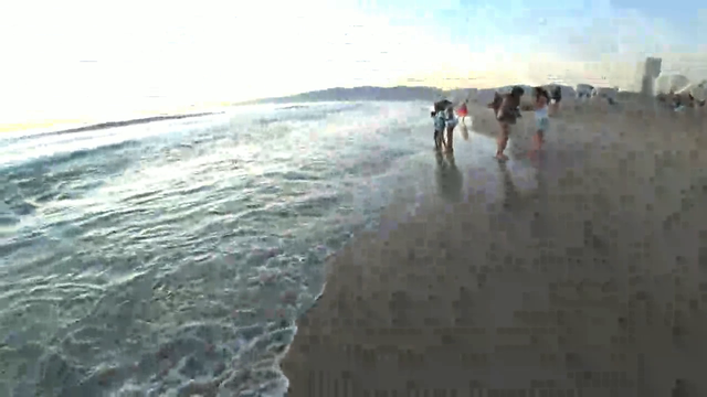Autistic man trying to put shoes on in the ocean.